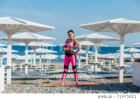 Brunette woman in sportswear sports fitness workout yoga on the beach by the sea 71475021
