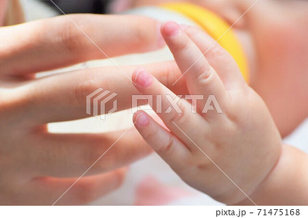 ミルクを飲ませるお母さんの手とその手を触る赤ちゃんの小さなかわいい手の写真素材