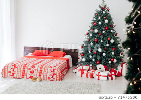 Christmas tree in the interior of the bedroom with a bed and pads for the new year Christmas tree in the interior of the bedroom with a bed and pads for the new year 71475500