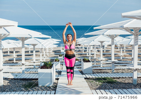 Beautiful woman engaged in fitness yoga gymnastics on the beach by the sea Beautiful woman engaged in fitness yoga gymnastics on the beach by the sea 71475966