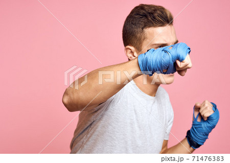 Guy in blue gloves on a pink background are boxing in a white t-shirt cropped view 71476383