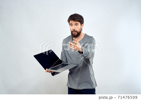 A man in a gray sweater with a laptop hands lifestyle technology communication internet work 71476509