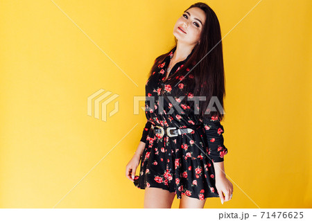 Beautiful fashionable brunette woman in dress on a yellow background Beautiful fashionable brunette woman in dress on a yellow background 71476625