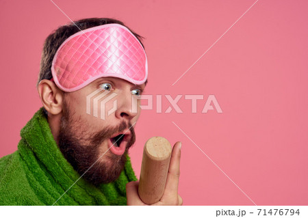 Portrait of a man in a pink sleep mask and a wooden rolling pin emotions green robe irritability model Portrait of a man in a pink sleep mask and a wooden rolling pin emotions green robe irritability model 71476794