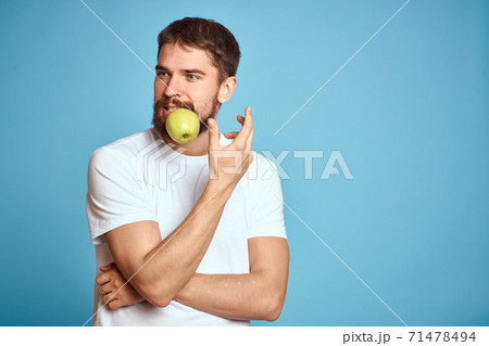 An energetic man with a green apple on a blue background gestures with his hands Copy Space emotions 71478494