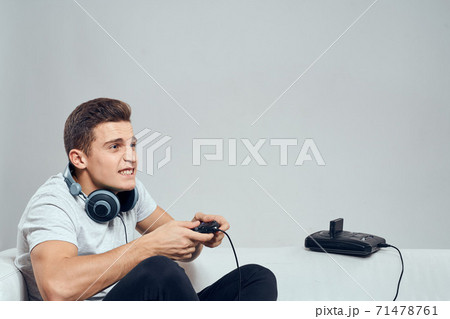 A man sits on the couch with headphones a video game set-top box entertainment fun A man sits on the couch with headphones a video game set-top box entertainment fun 71478761