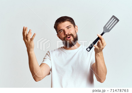 man with cooking shovel and white t-shirt close-up cropped view emotion gesturing with hand 71478763