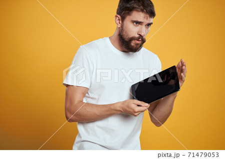 Man with a tablet on a yellow background in a white t-shirt new technologies businessman touch screen touchpad Man with a tablet on a yellow background in a white t-shirt new technologies businessman touch screen touchpad 71479053