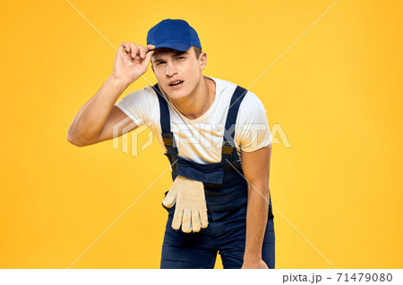 Working man in uniform of gloves rendering service yellow background 71479080