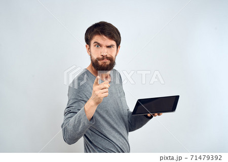 A bearded man with a tablet in his hands a gray jacket technology internet light background 71479392
