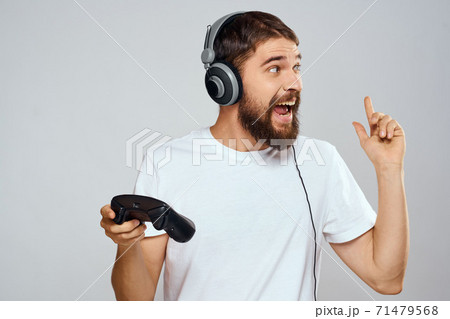 Man in headphones with gamepad playing hobby entertainment lifestyle light background 71479568