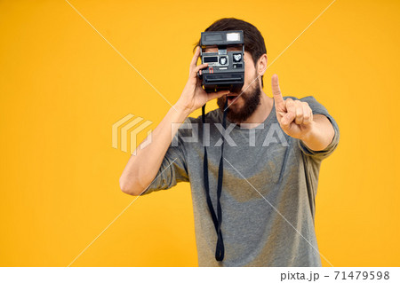 Male photographer with professional photo camera. Professional Creative approach studio yellow background 71479598