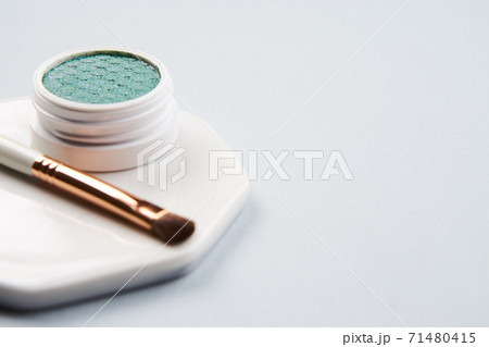 Green eyeshadow and makeup brush on white stand isolated background Green eyeshadow and makeup brush on white stand isolated background 71480415