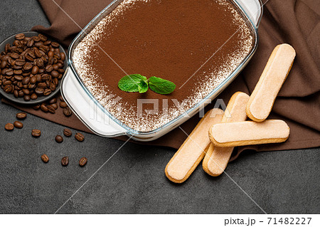 Traditional Italian Tiramisu dessert in glass baking dish and savoiardi cookies on concrete background Traditional Italian Tiramisu dessert in glass baking dish and savoiardi cookies on concrete background 71482227