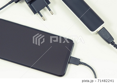 Smartphone with connected powerbank and plug of charger. Telephone charging Smartphone with connected powerbank and plug of charger. Telephone charging 71482241