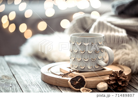 Coffee cup over Christmas lights bokeh in home on wooden table with sweater on a background and decorations. Holiday decoration 71489807