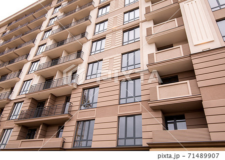 the facade of the multi-storey building is brown in color with black frame windows and architectural elements of molding and rusting, close up. the facade of the multi-storey building is brown in color with black frame windows and architectural elements of molding and rusting, close up. 71489907