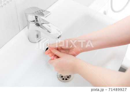 washing femle hands in a ceramic washbasin with a chrome faucet on water, bacteria of the covid-19 virus are washed off, close up faceless. washing femle hands in a ceramic washbasin with a chrome faucet on water, bacteria of the covid-19 virus are washed off, close up faceless. 71489927