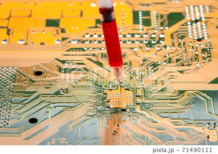 motherboard with contact paths of microcircuit and syringe with needle filled with red liquid, concept on topic of cospirology of vaccination and chipization of society given control to population. 71490111