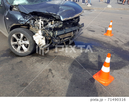 wrecked suv car after a head-on collision damaged fender and engine compartment of vehicle fenced by orange traffic cones drips of spilled oil from the engine, close up front accident. wrecked suv car after a head-on collision damaged fender and engine compartment of vehicle fenced by orange traffic cones drips of spilled oil from the engine, close up front accident. 71490316