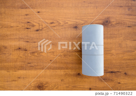 Gray cylindrical modern lamp mounted on a wooden wall of a building facade with a copy space, close up lantern nobody. 71490322