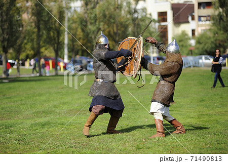 Reenactors dressed in armor of Old Russian footmen reconstructing swords fight 71490813