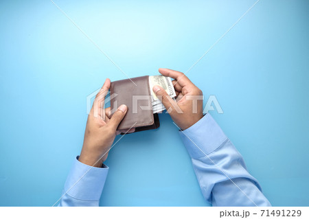 man hand taking cash out from wallet on blue background  71491229