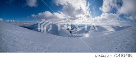 Snow and wind formed ice formations covered winter mountain plateau, tops with snow cornices in far. Magnificent sunny day on picturesque beautiful alpine ridge. 71491486