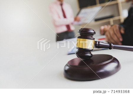 Wooden gavel on table in lawyer's office. Lawyer having team meeting with the client. Concepts of law, advice, legal services. Wooden gavel on table in lawyer's office. Lawyer having team meeting with the client. Concepts of law, advice, legal services. 71493368