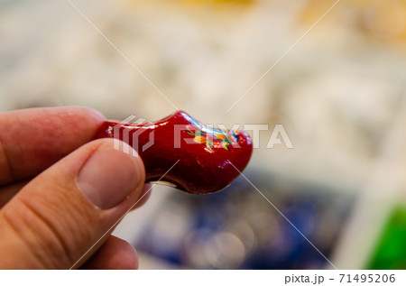 Kinderdijk, The Netherlands, August 2019. Souvenir Dutch clogs, produced in different shapes and colors, make a good show in the display. The tourist's hand touches them to observe them. 71495206