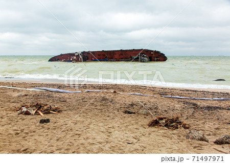 dirty sandy beach in the remnants of garbage after the ship wreck near the shore of the sea, a man-made disaster with water pollution in cloudy weather, nobody. dirty sandy beach in the remnants of garbage after the ship wreck near the shore of the sea, a man-made disaster with water pollution in cloudy weather, nobody. 71497971