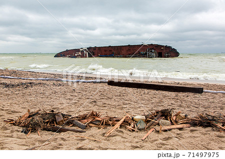 the consequences of a tanker wreck on a sandy beach a protective barrier and the remnants of trash broken boards. the consequences of a tanker wreck on a sandy beach a protective barrier and the remnants of trash broken boards. 71497975