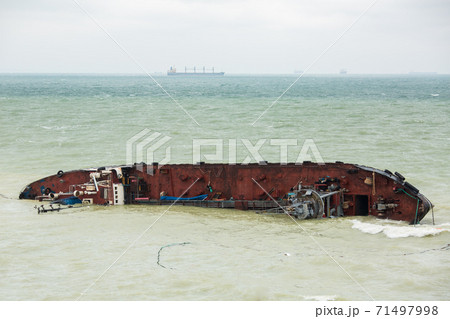 a cargo ship a tanker ran aground and rolled over into the sea with waves in cloudy weather, a man-made disaster, pollution of the marine ecosystem by emissions from the vessel. 71497998