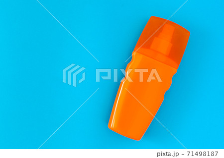 sunscreen in an orange bottle with a spray bottle and a transparent cap lies on a blue background top view with place for text. 71498187