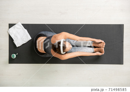 View of young active woman in headphones and tracksuit exercising on mat View of young active woman in headphones and tracksuit exercising on mat 71498585