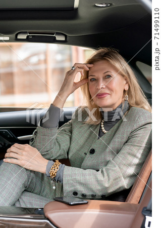 Smiling elegant businesswoman looking at you from backseat of taxi cab Smiling elegant businesswoman looking at you from backseat of taxi cab 71499110