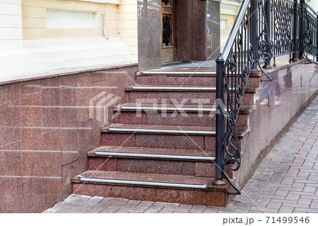 marble staircase with a rise to the front door with rubber non-slip stripes and black forged handrails, threshold with steps entrance close up. 71499546