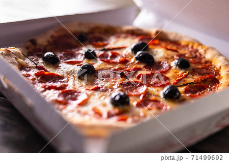 Pizza in a cardboard box on table ready to Pizza in a cardboard box on table ready to 71499692