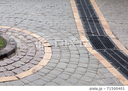 pedestrian square made of stone tiles with a black lattice drainage system, close up. pedestrian square made of stone tiles with a black lattice drainage system, close up. 71500401