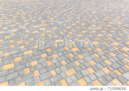 paving stone tiles of square and rectangular shape of gray and yellow are paved in perspective, closeup of the road surface. 71500638
