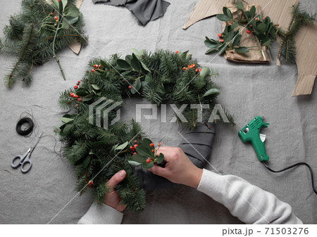 Man making Christmas wreath. New year holiday decoration Man making Christmas wreath. New year holiday decoration 71503276