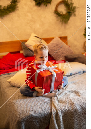 Funny child holding Christmas gift in hand. Christmas concept. 71505280