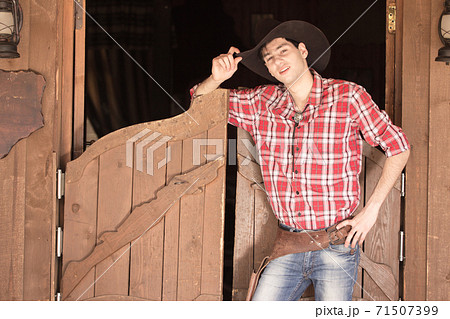 Cowboy in hat standing near saloon entrance Cowboy in hat standing near saloon entrance 71507399