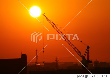 綺麗な丸い夕日と働く重機  夕日の位置が高い 71509131