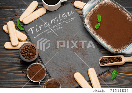 Traditional Italian Tiramisu dessert in glass baking dish, cup of coffee and savoiardi cookies on stone serving board with chalk inscription sign on wooden background Traditional Italian Tiramisu dessert in glass baking dish, cup of coffee and savoiardi cookies on stone serving board with chalk inscription sign on wooden background 71511832