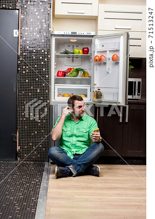 Young Man Sitting In Front Of Fridge Young Man Sitting In Front Of Fridge 71513247