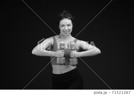 Brutal athletic woman pumping up muscules with dumbbells 71521267