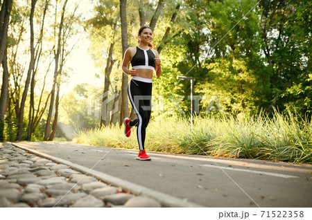 Morning training in park, woman running on walkway Morning training in park, woman running on walkway 71522358
