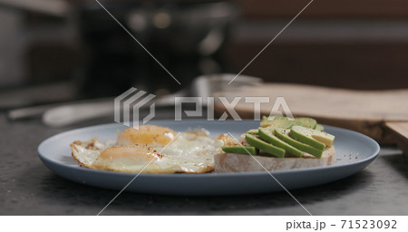 Slow motion man seasoning fried egg on blue plate Slow motion man seasoning fried egg on blue plate 71523092