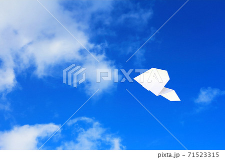 大空を飛ぶ紙ヒコーキの写真素材